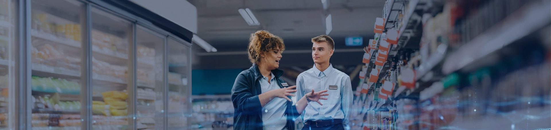Two field marketing professionals engaged in a discussion about shelf visibility and product placement in a supermarket aisle.