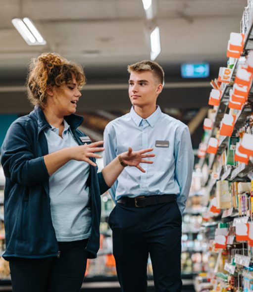 A field marketing team discussing product placement in a supermarket aisle, showcasing FMCG retail execution and compliance.