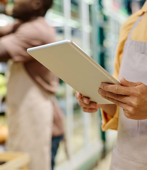 A field marketing agency representative holding a tablet while conducting a store visit for in-store compliance and promotional support in a grocery setting.